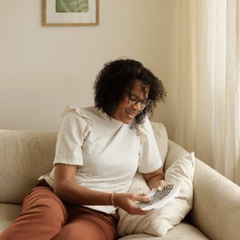 A woman sitting on a coach doing a card reading with the original cards